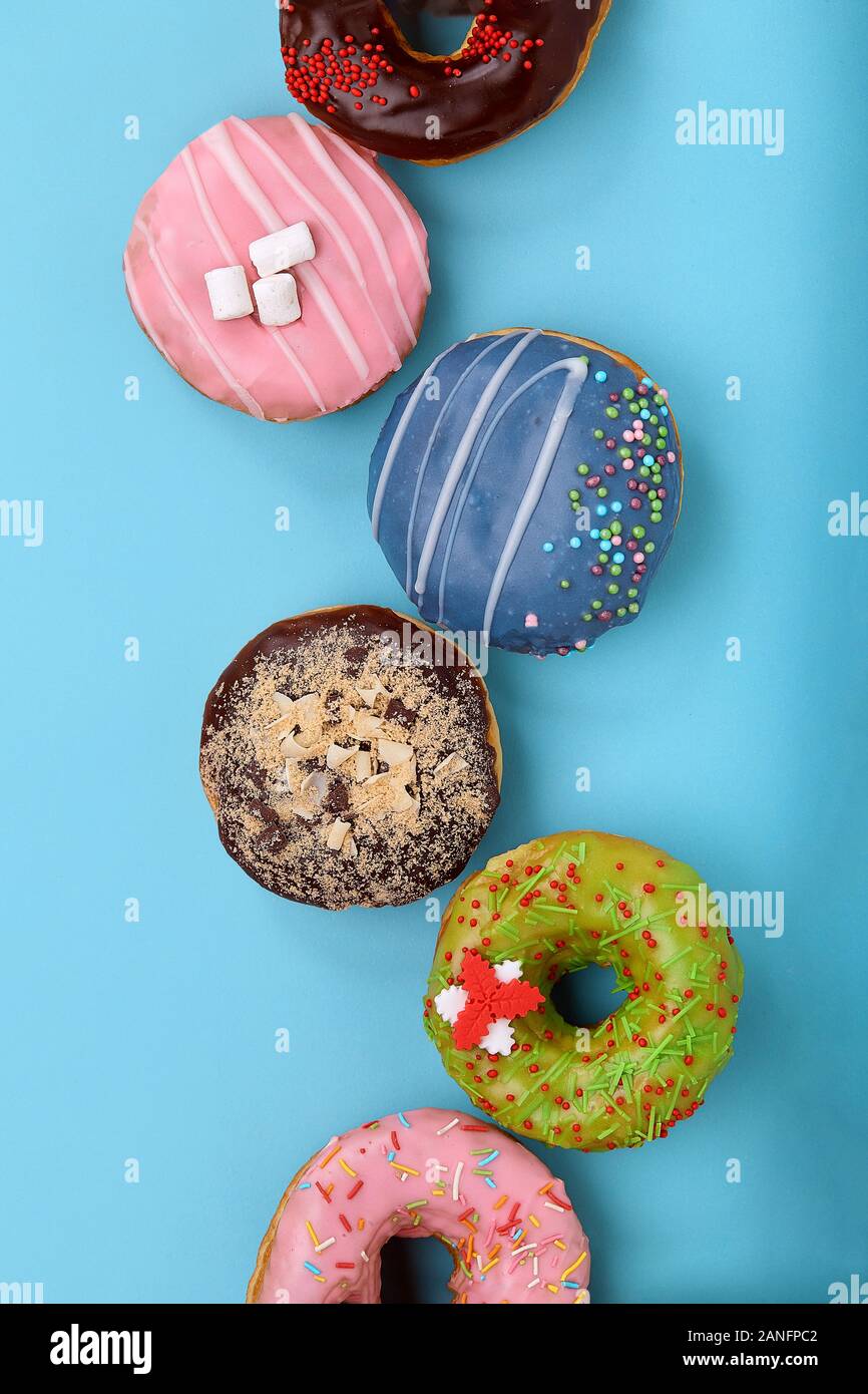 Süße bunte Donuts auf blauem Hintergrund, die in der Form von ...
