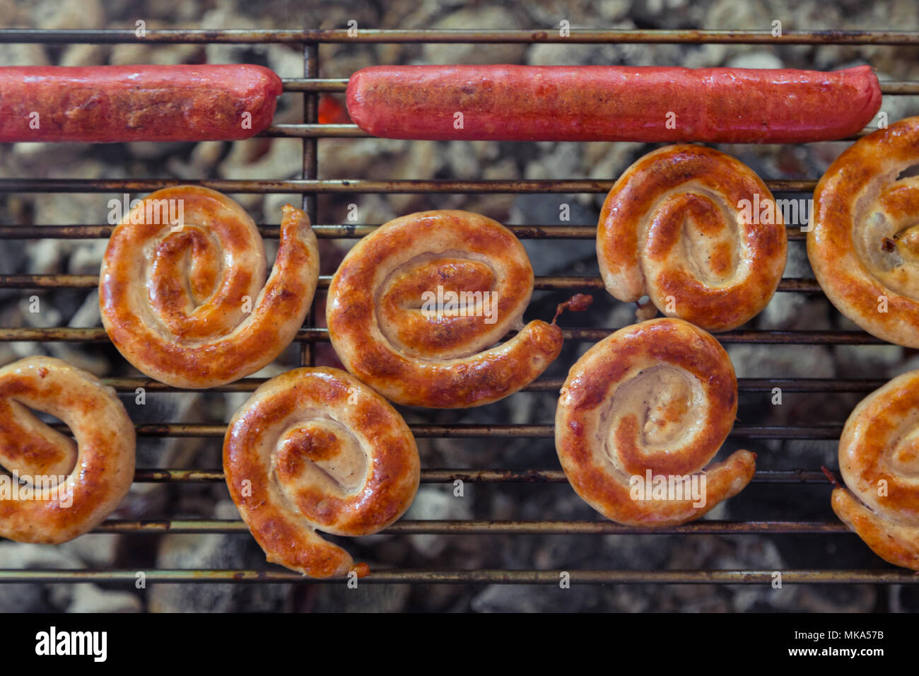 Gegrillte Würstchen auf den brennenden Grill. Cumberland Wurst, Spirale ...